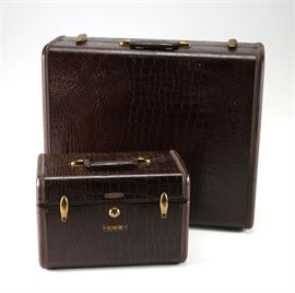 Vintage Shwayder Bros. Inc. Samsonite Travel Case: A pair of Shwayder Bros. Inc. Samsonite travel cases. This includes a travel case and a vanity train case. The pieces feature a stamped faux alligator vinyl hardcover with tan fabric lined interiors. The pieces feature gold toned hardware and logo plates along with an initial plate on the vanity case that reads, “LGR”.