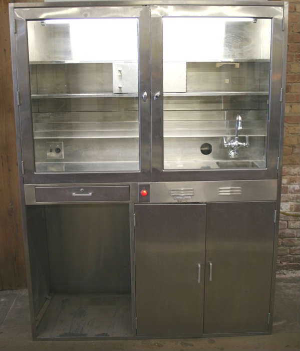 Industrial modern stainless steel lighted pharmacy cabinet. Came out of ICC nursing school. Has space on bottom left for small refridgerator....standard mini fridge fits in there perfect. Has sink and lockable storage above and storage below. Has tiered storage area inside. Would make great bar in loft or office. Measures 23" deep x 5' wide and 80" tall.