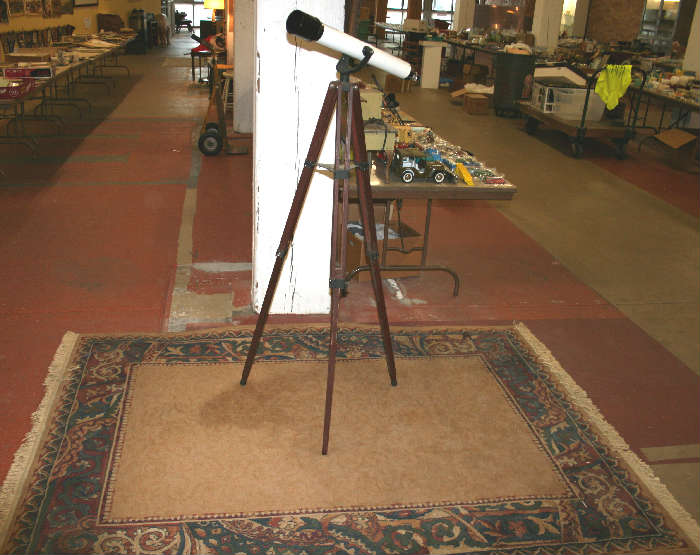 Tasco telescope sitting on a modern room size rug.