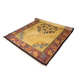 Handwoven Indian Area Rug: A handwoven Indian area rug. This rug features a central medallion in a palette of black, green, gold tones, and red. This rug also features a single border in a palette of red, blue, and gold tones. The reverse of the rug has a tag that reads “Registration No: 19344, Made in India, Carpet No: 4530”.