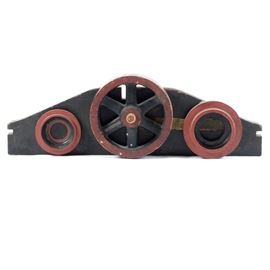 Large Wooden Industrial Form: A large wooden industrial form designed with three circular shapes mounted to a thick arched board. The larger round form to the center is a wheel shape with wooden spokes, has a rustic painted finish in red, yellow and black.