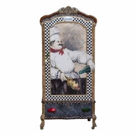 Richard and Maggie Mantia Hand Painted and Decoupage Kitchen Cabinet: A hand painted and decoupaged wooden French Provincial style cabinet by Richard and Maggie Mantia. It features a white floral pediment on an arched top, a tall, narrow body with a fitted door and a bottom drawer with a serpentine front and dovetail joinery, and clawed feet on casters. The door is painted with a stocky chef preparing food, as well as a black and white checkerboard pattern trim around the perimeter. “Mantia” is signed at the bottom right. The shoulders are painted like faux tan marble and decorated with travel memorabilia decoupaged within checkerboard trim. The bottom drawer is painted a gray faux marble with red and green pepper handles, with brown and black checkerboard and animal stripe patterns on the top and bottom aprons. The legs are painted with a faux leopard pattern. Opening the door reveals a decoupaged interior with five glass shelves.
