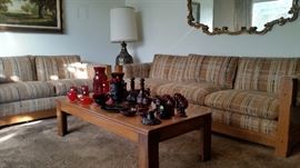 Living room set includes sofa and love seat. Coffee table holds lovely collection of Cape Code and other red glass pieces. Also included: wood corner table, lamp, large ornate wall mirror and framed landscape.