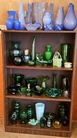 Nice collection of light blue and green glass on a three-shelf bookcase.