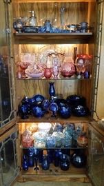 Multi-colored glassware, including a collection of covered candy dishes. (Curio cabinet is not for sale.)