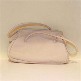 Miu Miu Leather Handbag: A Miu Miu handbag, made in Italy from cream colored leather. The bag features a rectangular body with a rounded base, two handles and a gold tone zipper. The interior is a pale mauve brushed cowhide with a side compartment and an interior label marked, “Miu Miu Made in Italy.”