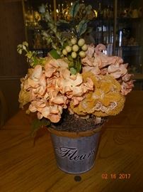 A beautiful decorative artificial flower arrangement with metal bucket.