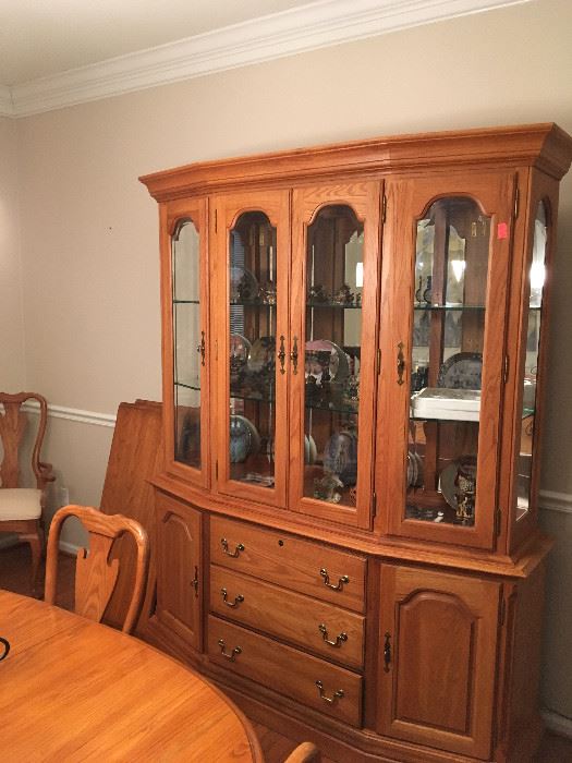 This solid oak china cabinet features glass shelves with plate grooves along with lights to highlight your treasures.  This cabinet which compliments the dining table and six chairs -- retailed for $8,000.00 all together.