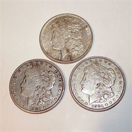 Three 1921 Silver Morgan Dollar Coins: A group of three 1921 Silver Morgan dollar coins. Designer: George T. Morgan. Mintage: 44,690,000. Metal content: 90% silver, 10% copper. Diameter: 38.1 mm. Weight: 26.73 grams. Circulated. Good condition.