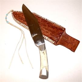 Custom Vintage Bone Handle 8" Bowie Knife with Steel Pommel and Carved Leather Sheath: A custom vintage bone handle 8" bowie knife with steel pommel and decorative carved leather sheath. Knife features an angular clip point blade, full tang, and steel capped white bone handle including pommel with two brass rivets. Custom leather belt sheath features flat multi strand wrap stitching all along outer edges and embossed surface design of graphic and natural patterns.