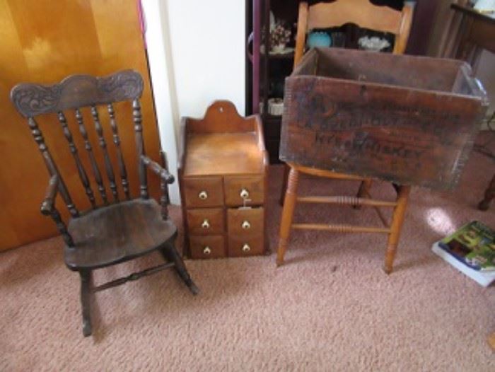 Pressed back oak child's rocking chair on the left. Spice wall cabinet, center, and pine box on the right. 
