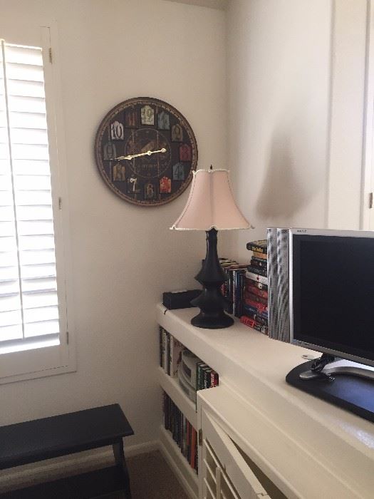 Flat Screen T.V. on a swivel base.  High-end lamp (brand is Stanley) from Fiesta Furnishings with high-end lampshade.  Neat wall clock distressed.  Books and a small bookshelf
