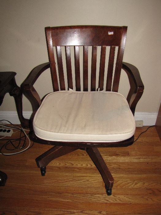 A wooden, wheeled desk chair.