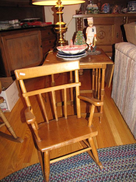 A child-sized rocking chair and end table, next to the almost visible loveseat.