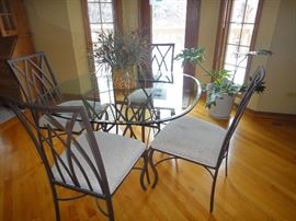Wrought iron glass kitchen table with matching chairs .