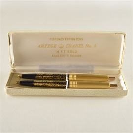 Arpege/Chanel No. 5 14K Yellow Gold Pen Set: A set of two 14K yellow gold painted pens from Arpege/Chanel No. 5 in their original box. Both are ball point with springs. They are in a white leather case.