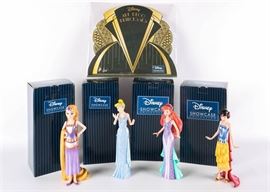 Disney "Art Deco" Princess Figurines: A grouping of four Disney princesses from Enesco’s Disney Showcase Art Deco Collection. The set includes Rapunzel, Cinderella, Ariel, and Snow White wearing their traditional costumes as re-interpreted in the Art Deco style. Each figurine is fashioned from stone resin, is marked to the bottom, and presented in its original box.