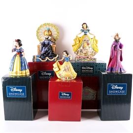 Snow White and the Evil Queen Figurines: A grouping of Snow White and the Evil Queen figurines. The figurines are part of the Disney Traditions Collection designed by Jim Shore for Enesco. Included in the set are Castle in the Clouds featuring Snow White in ball gown that depicts her castle in the middle of the skirt, Fairy Tale Endings From The Fairest Of Them All depicting Snow White in ball gown, Evil Enthroned figurine of the Evil Queen wearing her crown and sitting on her thrown. Also included in this set are two Couture de Force Masquerade Figurines of the Evil Queen and Snow White. Each comes in the original packaging and is marked to the bottom.