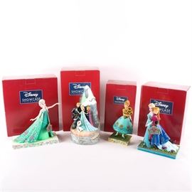 Elsa and Anna Figurine Collection from Disney's "Frozen": A collection of Jim Shore figurines depicting characters from Disney’s film Frozen. Each figurine is part of the Disney Showcase Collection and features colorful, folk art qualities typical of Jim Shore designs. The grouping includes figurines titled, Spring in Bloom, Celebration of Spring, Sisters Forever_, and "Worth Melting For. Each piece is crafted from resin, marked to the bottom, and presented in its original box.