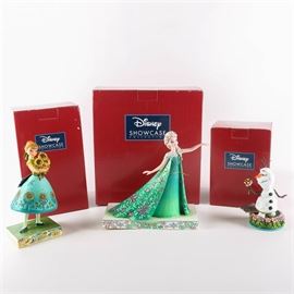 Frozen Spring and Summer Collection: A collection of Jim Shore figurines depicting characters from Disney’s film Frozen. Each figurine is part of the Disney Showcase Collection and features colorful, folk art qualities typical of Jim Shore designs. The grouping includes figurines titled, Spring in Bloom, Celebration of Spring, and Olaf Dreaming of Summer. Each piece is crafted from resin, marked to the bottom, and presented in its original box.