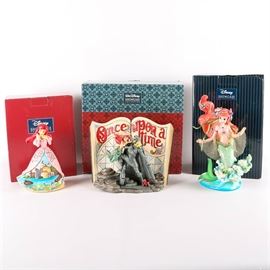 Ariel Figurines from Disney's "The Little Mermaid": A collection of whimsical Disney Little Mermaid figurines. The figurines are entitled Sanctuary by the Sea depicting Ariel with legs in a ball gown in the Prince’s castle, Undersea Dreaming a 3-D story book plaque that reads “once upon a time”, and an Ariel Figurine with fins underwater. The figurines, produced by Enesco, are part of the Disney Traditions Collection designed by Jim Shore. Each piece is marked to the bottom and comes in original box.