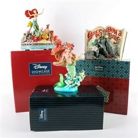 The Little Mermaid Figurine Collection: A little Mermaid figurine collection. The grouping comes with three stone resin figurines including “Couture de Force” Ariel figurine numbered 4037524 from the Disney Showcase Collection and two Disney Traditions figurines designed by Jim Shore for Enesco including “Undersea Dreaming” storybook numbered 4031484, and a “Under the Sea” music box figurine numbered 4039073. Each figurine comes in the original box.
