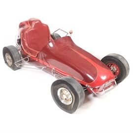 1930s Midget Car Style Racecar: A 1930s racecar. This vehicle is in the “midget car” style with a burgundy and red painted metal body, Firestone “Micro 500” Gum Dipper tires, chrome side rails, wooden shift knob, and a leather seat. The Briggs & Stratton crankcase is model 80332.