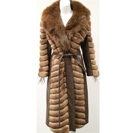 1960s Donenfeld's Mink and Leather Coat: A 1960s Donenfelds mink and leather coat. The coat has a tufted style in shades of brown mink with panels of brown leather in a wrap around style with a leather belt. The coat has a large fur collar and flared arms with a brown lining. The coat is labeled “Donenfelds, Dayton” and has an interior monogram “Mary N. Harrington”.