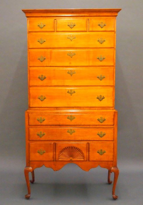 An 18th century New Hampshire Dunlap school Queen Anne Period Maple highboy.  Upper case with a molded cornice over five long lip molded drawers, the upper with a three drawer facade, on a base with three long drawers, the lower with a three drawer facade and carved central fan, over a scalloped apron, all supported by cabriole legs with pad feet.  Original brass hardware, pine secondary wood.  Older refinishing, some wear, three restored knee returns, small pieced repair to crown, shrinkage cracks in sides of base.  40 x 20 1/2 x 79 1/2" high. ESTIMATE $3,000-5,000