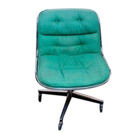 Green Upholstered Pollock Desk Chair: A green upholstered pollock desk chair. This office chair has a one-piece back and seat with a curved silver tone rim and tufted blue-green upholstery. The chair has a pedestal base and four caster wheels.