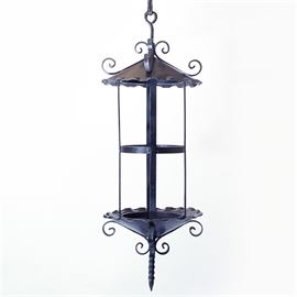 Cast Iron Pendant Light: A cast iron pendant light. This decorative hanging lantern has a pointed roof and base with ruffled edges, both decorated with scrolled bands, and a twisted bottom finial. The piece hangs from a chain by an attached loop at the top.