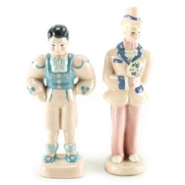 Kay Finch Pottery Figurines: A pair of Kay Finch pottery figurines. Kay Finch Ceramics were made in Corona Del Mar, California, from 1935 to 1963. The pair depicts a Victorian “Godey man” with blonde hair and a “Peasant boy” with black hair, both in pink and blue outfits and resting on a small base.