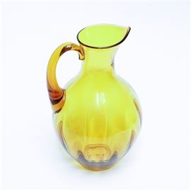 Vintage Hand Blown Blenko Glass Pitcher: This is a vintage hand blown Winslow Anderson design optic rib glass pitcher by Blenko Glass. It’s model number is #991. The pitcher features the color gold, which was only used by Blenko from 1955-1958. There is a rough pontil mark on it’s base, which indicates the hand blown nature of the glass.