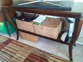 Wonderful console table. Dark wood finish with canned bottom shelf