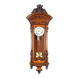 Antique Vienna Regulator Clock Circa 1860: An antique Vienna Regulator clock circa 1860. This wall clock features a walnut finish. It has a carved adornment above an arched pediment. A pair of fluted columns flank the glass on the front of the door, with the clock and pendulum within. To the bottom are several inverted turned finials.