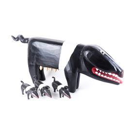 1992 Garland and Minnie Adkins Wood Sculpture "Mother Pig and Piglets": A 1992 wood sculpture set by folk art artists Garland and Minnie Adkins titled Mother Pig and Piglets. This set includes three sculptures, one of a sow and three of smaller piglets, each painted black with a white stripe and red mouth. The sow figure is marked on the bottom of three feet, “1992, G&M Adkins, ©”.