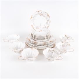 Haviland & Co. Limoges China Assortment: A Haviland & Co. Limoges china assortment. This grouping of eighteen pieces includes two dinner plates, one luncheon plate, three dessert plates, six saucers and six cups. The pieces are in a matching pattern of gray and pink florals with gold trim accents. All pieces and branded to the underside.