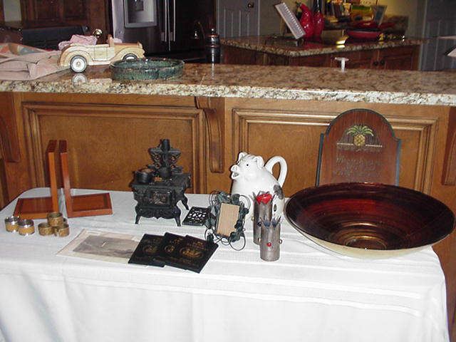 Decorative items incuding wood bookends, doll house iron stove, contemporary bowl, candlesticks, piggy pitcher, small woodblock prints, frames, welcome signs and more