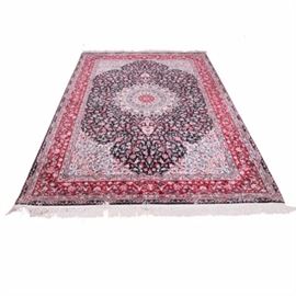 Handwoven Persian Inspired Area Rug: A hand woven Persian inspired area rug. This rug comprises a black field with a round central medallion featuring a foliate pattern in a palette of burgundy, rose and pale blue. A compound border features a field of burgundy with additional foliate designs. Natural warp fringe is attached at either end.