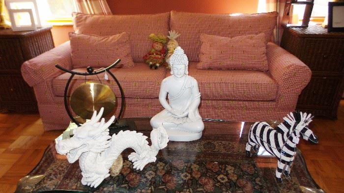 Sofa Sleeper with unique decor items: Buddha, zebras, Dragons. Glass and brass antique coffee table, 2 wicker end tables with file drawers. Traditional style area rug