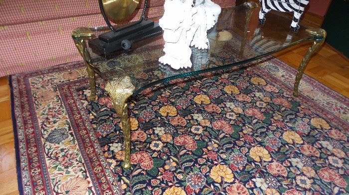 Thick glass coffee table with carved brass legs.  Traditional style rug