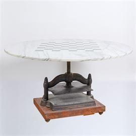 Marble Top Adjustable Chess Table: A marble top adjustable chess table. This white and black marble circular table top features a chess board inlay standing on a pedestal style adjustable stand with a wooden base on padded feet. This item is unmarked.