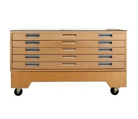 Drafting Table and Flat File Cabinet: A drafting table and flat file cabinet. This maple-stained storage table features a glass top to display drawings and five flat file drawers with metal pulls. The table rests on four caster feet and has no apparent maker’s marks.