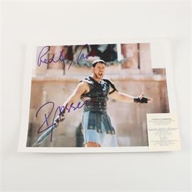 Russell Crowe and Ridley Scott Autographed "Gladiator" Photo: A Russell Crowe and Ridley Scott autographed photo. This 11″ × 14″ print with a thin white border depicts Crowe in a scene from the 2000 film Gladiator. The photo is signed in blue ink by both Crowe and director Ridley Scott.