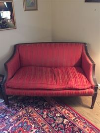 Upholstered red love seat with nail head decor.