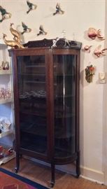 Antique oak display cabinet with curved glass, duck wall pockets, mercury glass bird figurine, kitschy fish wall plaques, parrot wall pocket