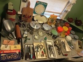 Vintage utensils including giant metal scoop, aluminum serving pieces with Pyrex liners, meat grinder, colorful Tupperware, airline flatware & more