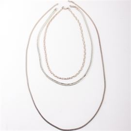Three Sterling Silver Chains: An assortment of sterling silver chains. Includes an 18" braided chain marked “Made in Italy 925”, a 19.5" herringbone chain marked “STG 925”, and a 29.5" herringbone chain marked “VIOR FGS Made in Italy 925”. All items feature a lobster clasp closure with a total approximate weight of 1.24 ozt.