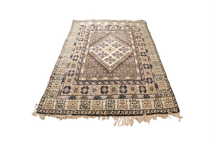 Hand Knotted Rug from Tunisia (ca. 1950): A hand knotted rug from Tunisia ca. 1950. The rug has a center diamond surrounded by various geometric shapes. Woven in a gray and beige color palette the rug has a white knotted fringe at each end.