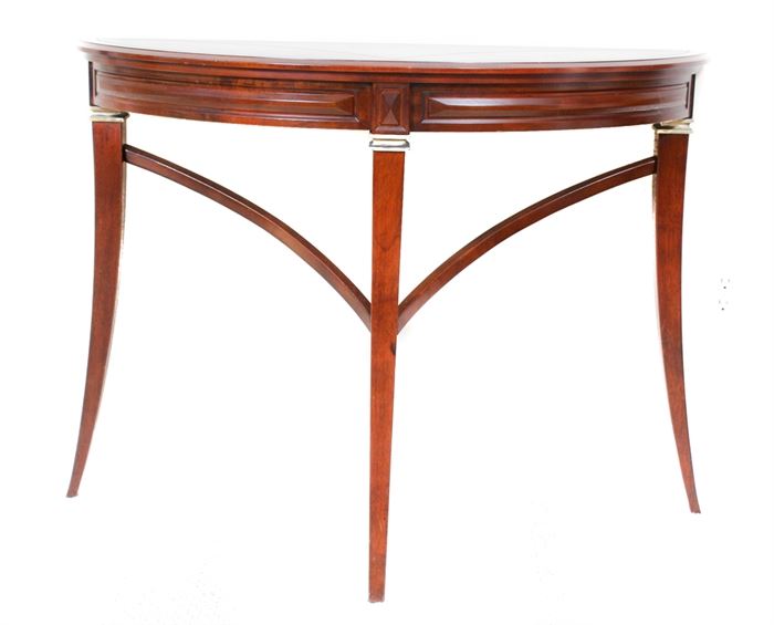 Bombay Company Mahogany Demilune Table: A mahogany demilune table by the Bombay Company. This piece is constructed from solid mahogany, and it features a demilune top over a carved apron and three tapered legs with brass accents at the top and curved stretchers.